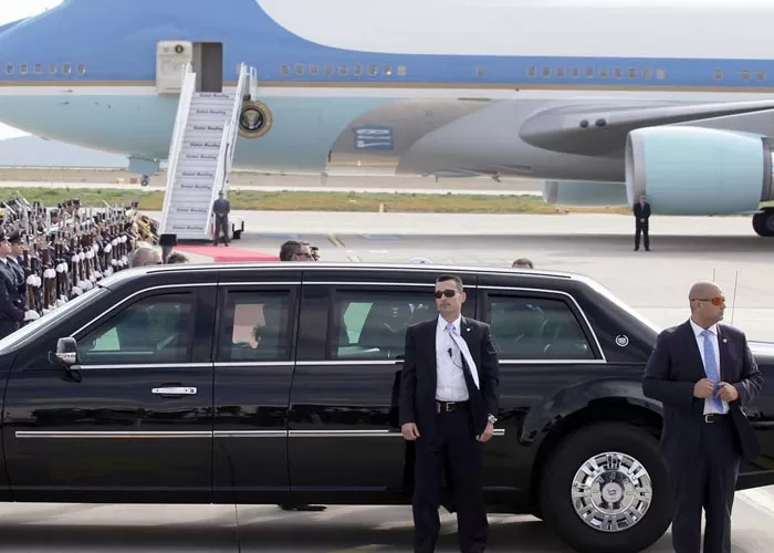 Personal security guards stand outside the car against the background of an airplane